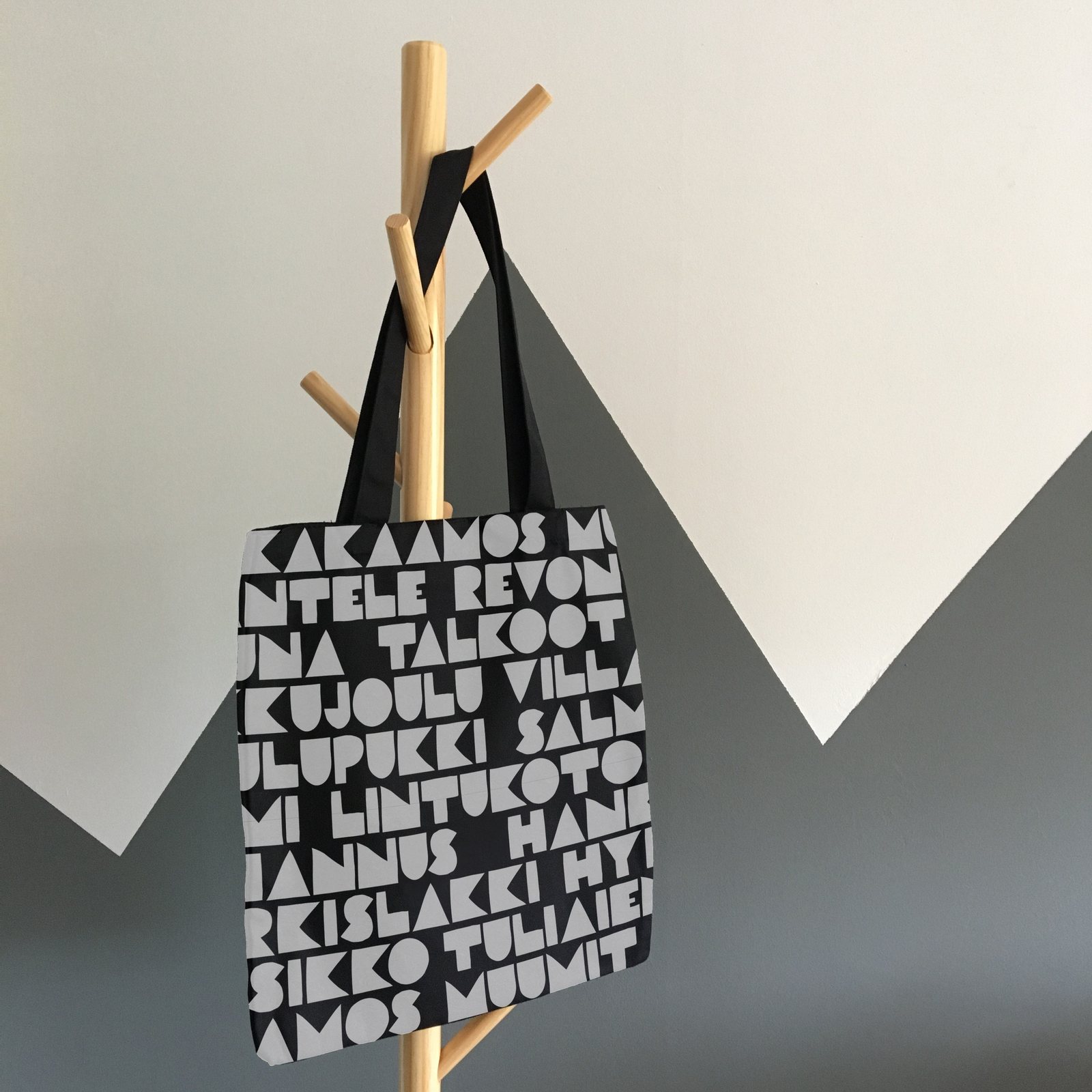 Black tote bag with a white Finnish word pattern