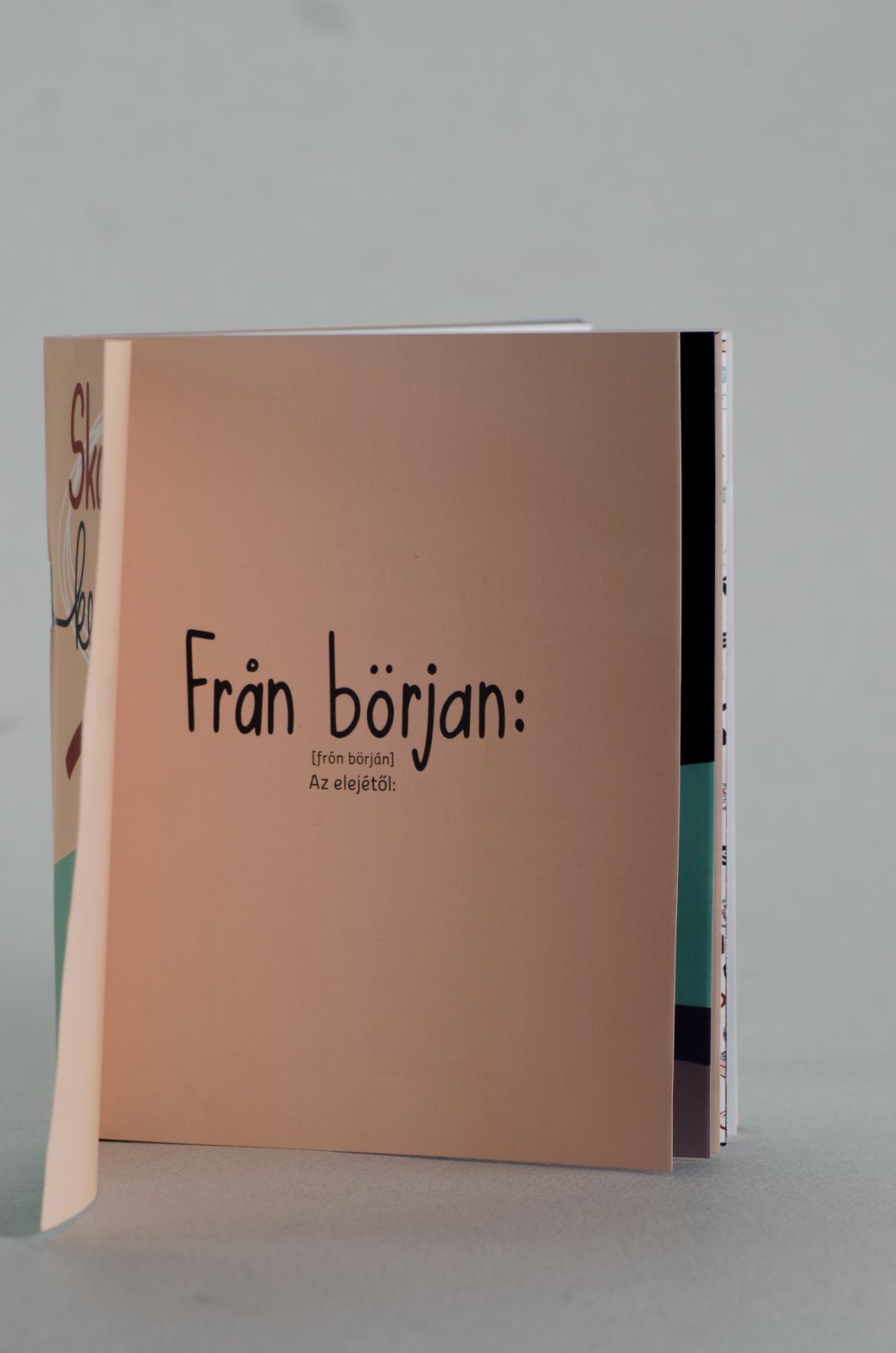 The printed booklet standing, with the Från början cover