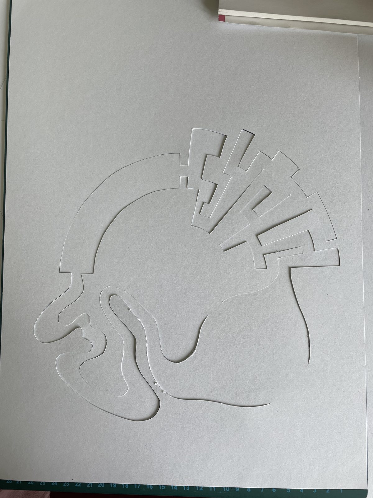Flat white sheet of paper with the maze and ring cut into it, before folding