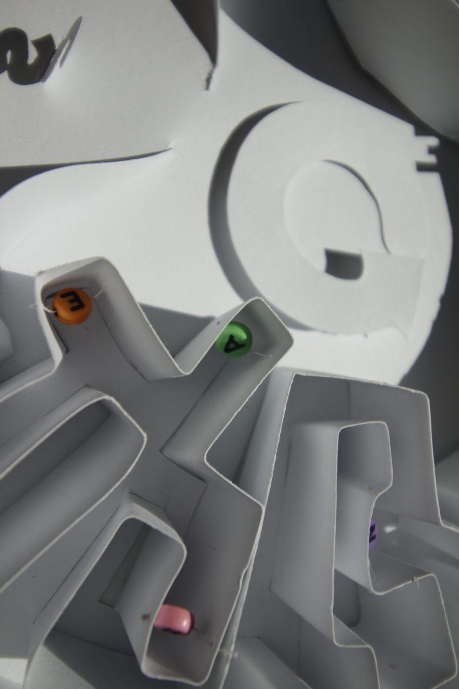 Paper maze with coloured letter beads in the corridors